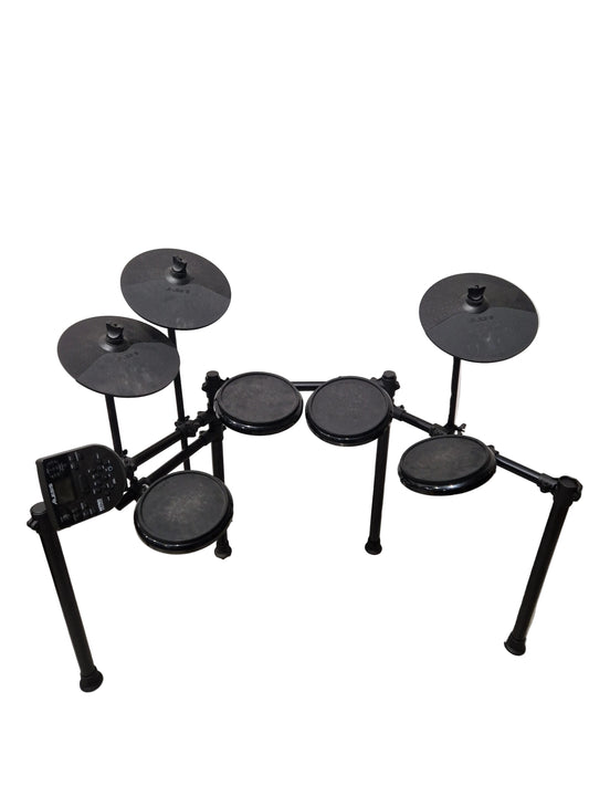Electronic drum set on a concrete floor with a white wall background