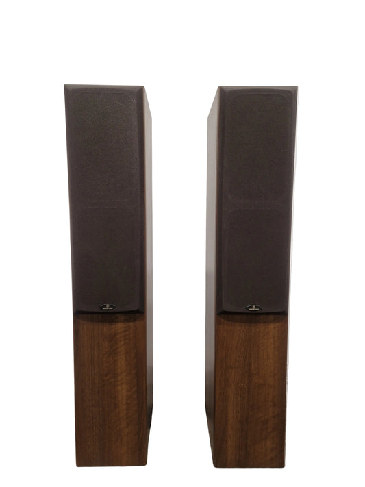 Pair of wooden speakers on a reflective surface with a neutral background
